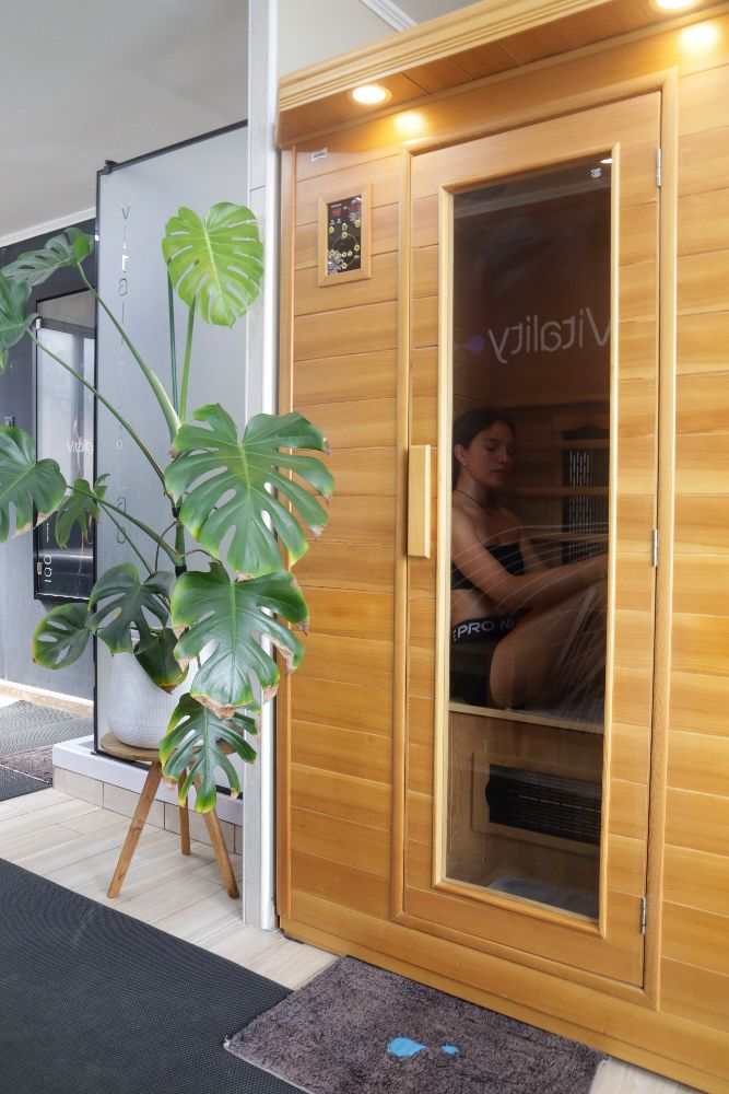 Sauna infrarrojo de madera con una monstera en la entrada