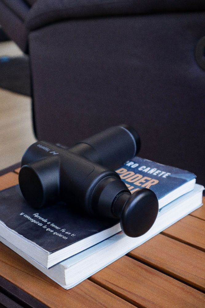 Pistola de masaje sobre un libro, en la zona de descanso